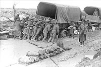 Canadiens en train d’aider à pousser un lorry sur une route endommagée par des obus, sur la crête de Vimy, Avril 1917.