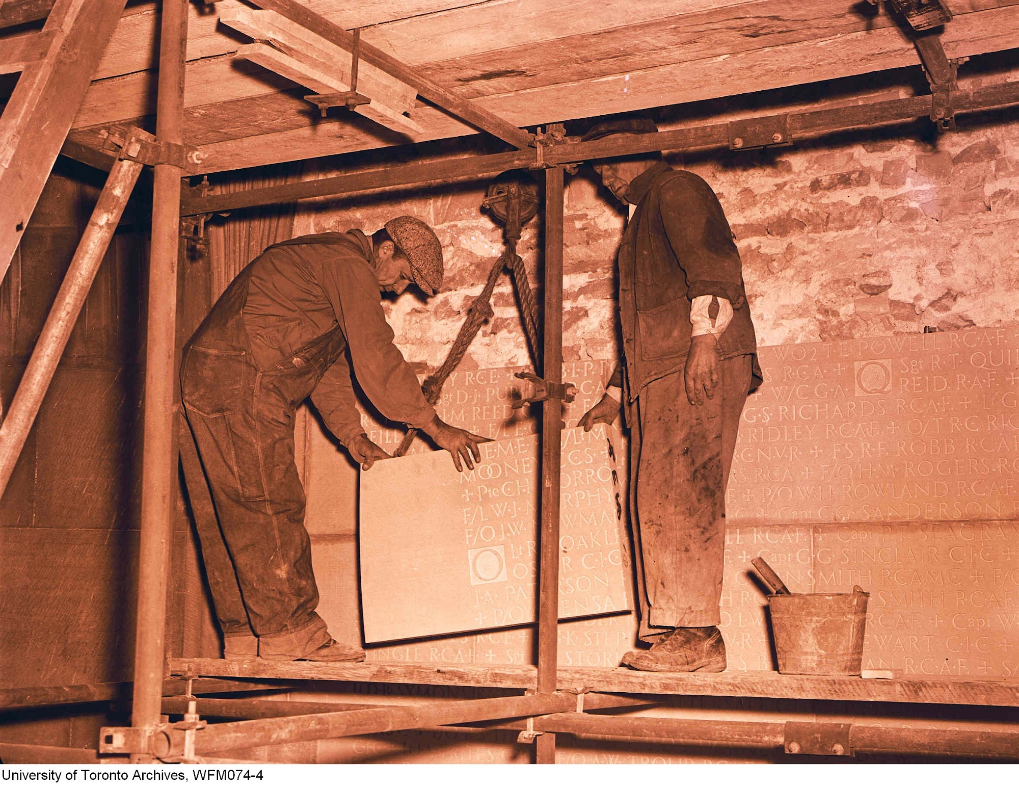 Adding the names of those killed in the Second World War. Stone masons lift a section into place. October 1949.