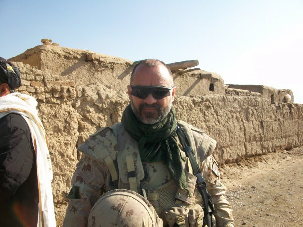 Bruno Plourde in military camouflage uniform, standing in front of a compound in Afghanistan.