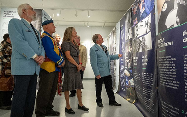 Des civils et des vétérans regardent des panneaux commémoratifs pour le 100e anniversaire de l’Aviation royale canadienne (ARC) au Musée royal de l’aviation de l’Ouest du Canada, au Manitoba.